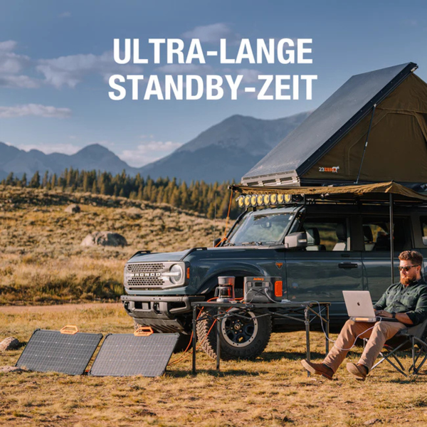 Camping-Szene mit tragbarer Powerstation und Solarpanels zur Stromversorgung von Laptop und Kaffeemaschine neben Geländewagen mit Dachzelt.