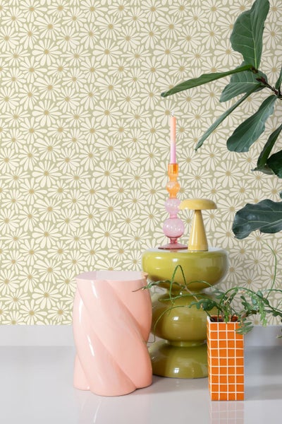 Heller Raum mit einer Tapete im floralen Retro-Gänseblümchen-Muster, kombiniert mit farbenfrohen Möbeln und grünen Zimmerpflanzen.