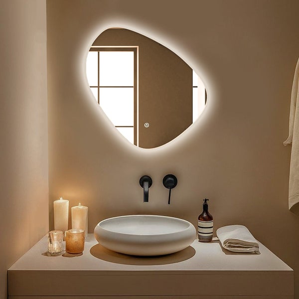 Moderner Badezimmerspiegel mit organischer Form und integrierter LED Beleuchtung über einem runden Aufsatzwaschbecken und Wandarmatur.