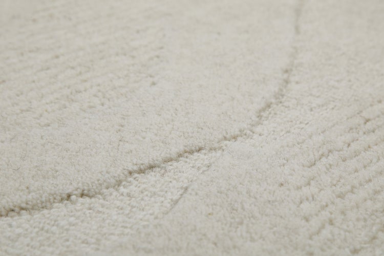 Nahaufnahme eines beigen Teppichs mit Hochflor und Reliefstruktur.