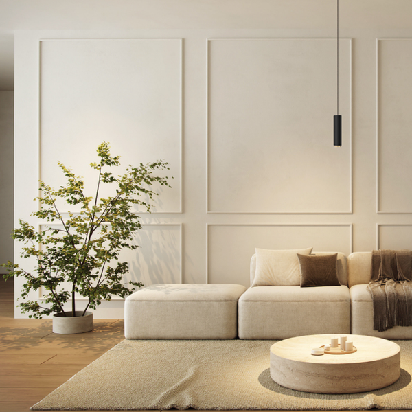 Wohnzimmer mit Couch, Tisch, Teppich und Zimmerpflanze vor einer dekorierten Wand
