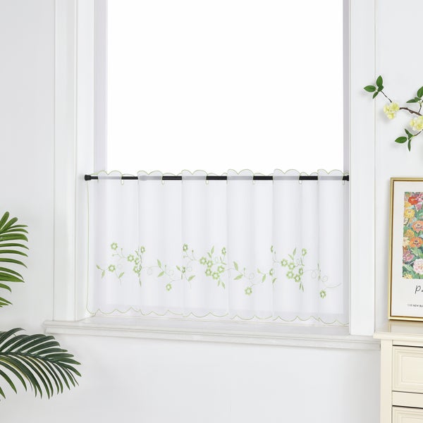 Kurze, weiße Fenstergardine mit grünen Blumenmotiven im Fenster