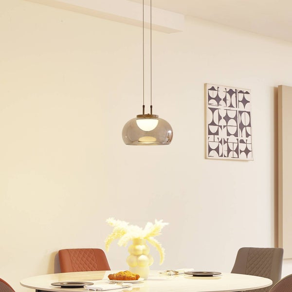 Moderne Pendelleuchte mit rauchgrauem Glasschirm über einem Esstisch in einem hellen, modern eingerichteten Esszimmer.