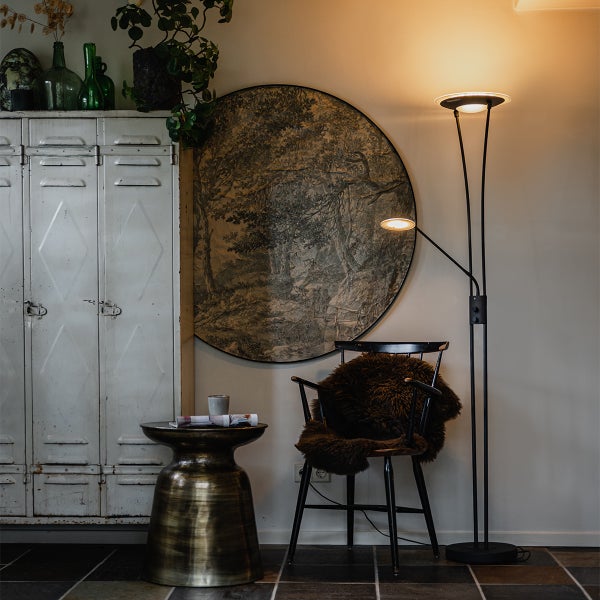 Innenaufnahme eines Zimmers mit einer Stehlampe, einem Stuhl mit Fell, einem Beistelltisch und einem Schrank