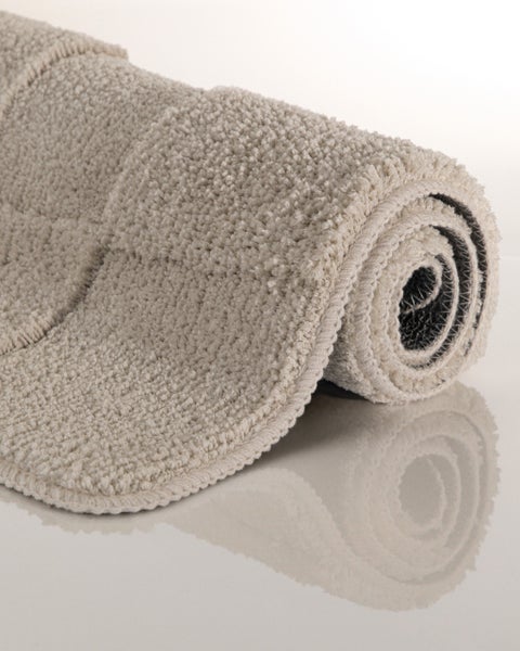 Eingerollte beige Badematte aus weichem Material mit strukturierter Oberfläche.