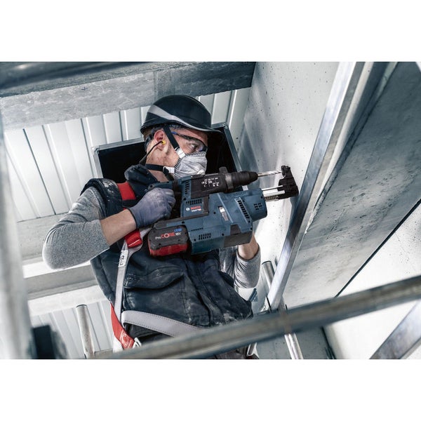 Ein Bauarbeiter bohrt mit einem Akku-Bohrhammer ein Loch in eine Betonwand.