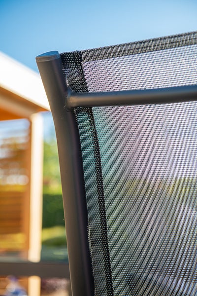 Nahaufnahme eines Gartenstuhls mit Metallgestell und Textilgewebe.