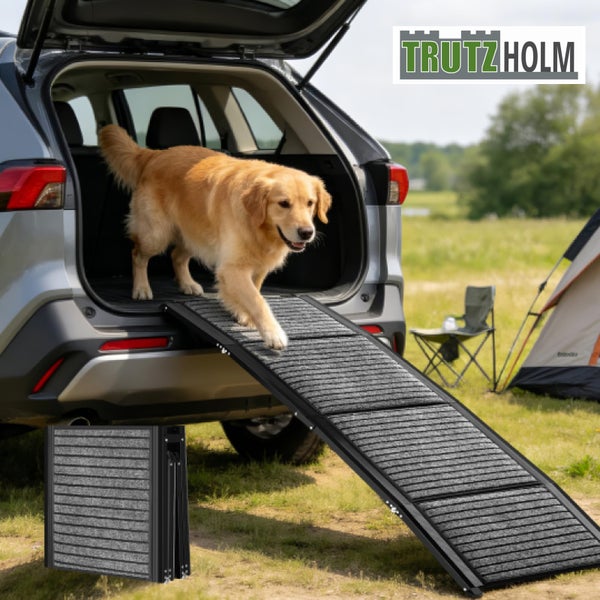 Klappbare, rutschfeste Hundrampe aus Aluminium an einem Auto, ein Hund läuft hinunter. Inklusive zusammengeklappter Rampe. Hell. Trutzholm Logo.