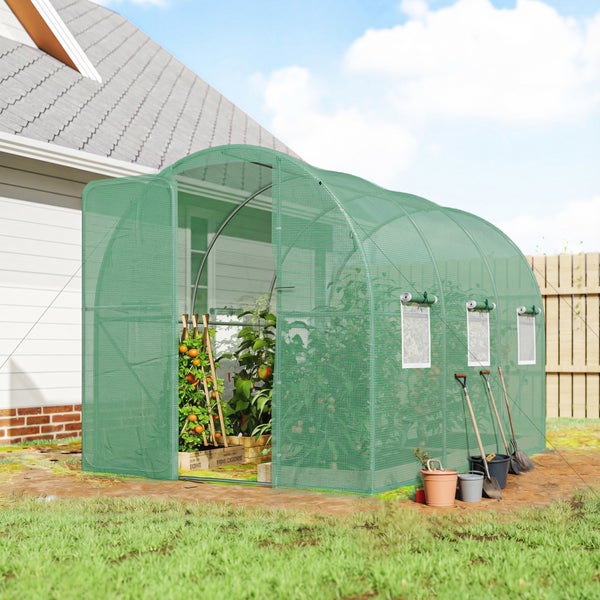 Grünes Folientunnel-Gewächshaus mit Metallrahmen und Gitterfolie im Garten, bestückt mit Tomatenpflanzen und Gartengeräten.