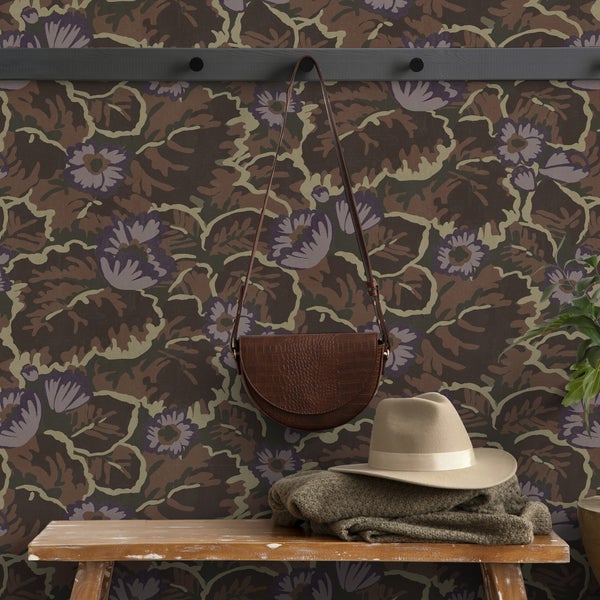 Dekoratives Interieur mit blumiger Tapete, Tasche und Hut auf einem Tisch