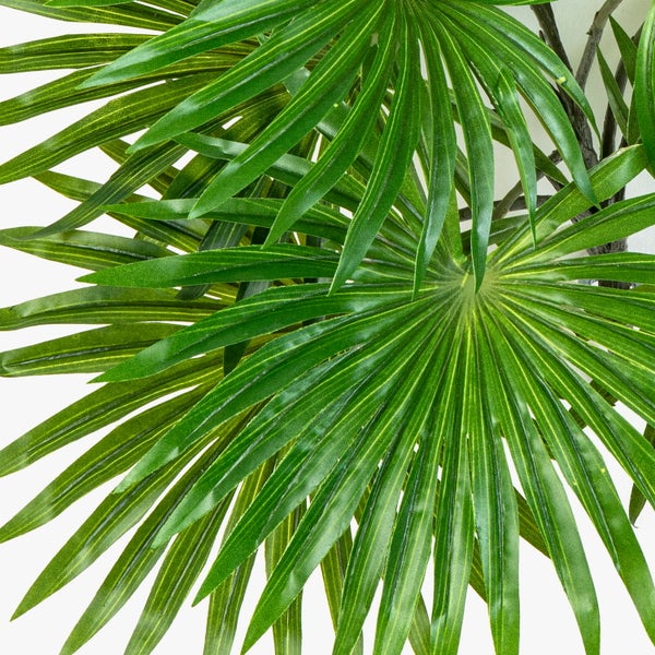 Künstliche Palme mit gefächerten grünen Blättern und strukturiertem Stamm.