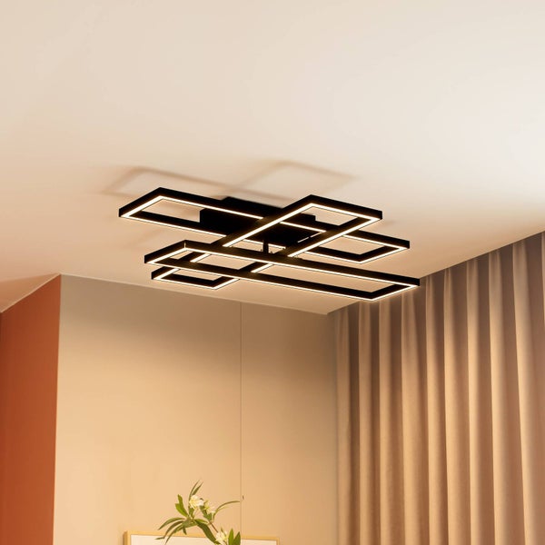 Moderne LED-Deckenleuchte in Schwarz mit ineinander verschlungenen rechteckigen Rahmen an einer hellen Zimmerdecke.