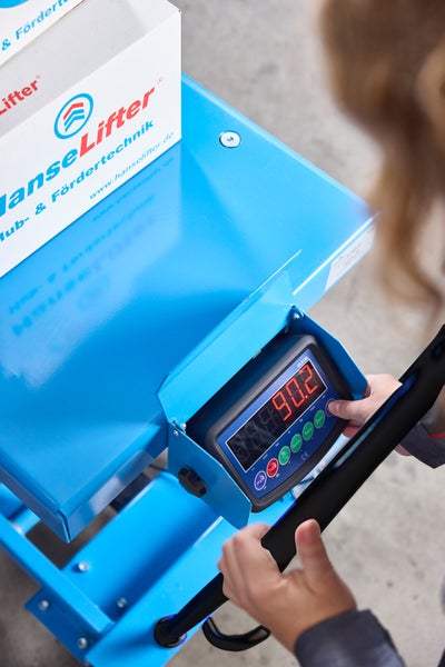 Digitale Gewichtsanzeige eines HanseLifter Hubtisches mit Waage, zeigt 90.2 Kilogramm bei der Bedienung durch eine Person.