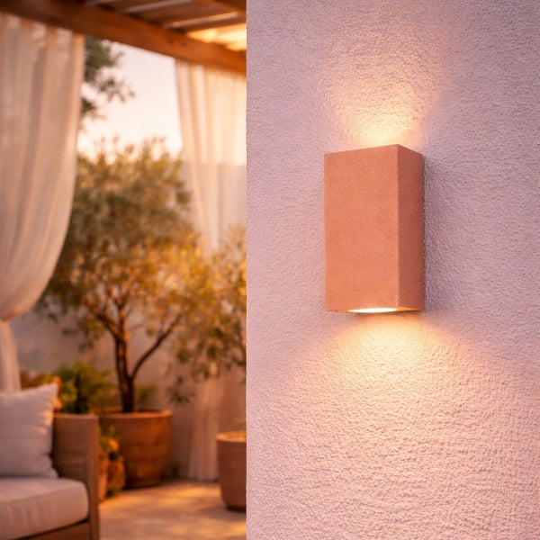 Moderne Wandleuchte in rechteckiger Form mit Up and Down Lichteffekt an einer Außenwand auf einer Terrasse montiert.