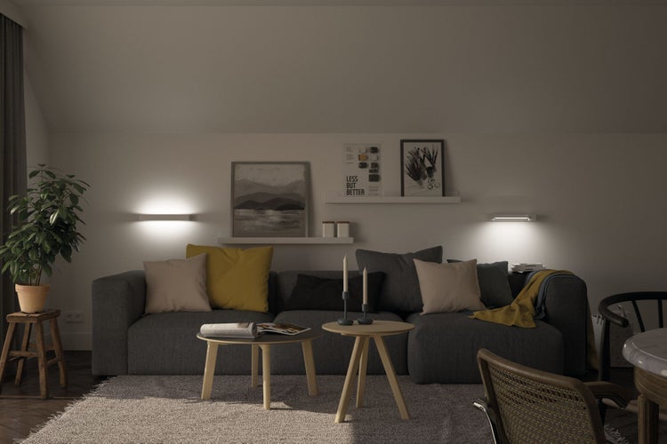 Wohnzimmer mit dunkelgrauem Sofa, zwei runden Couchtischen aus Holz und zwei Wandleuchten für gemütliche Beleuchtung.