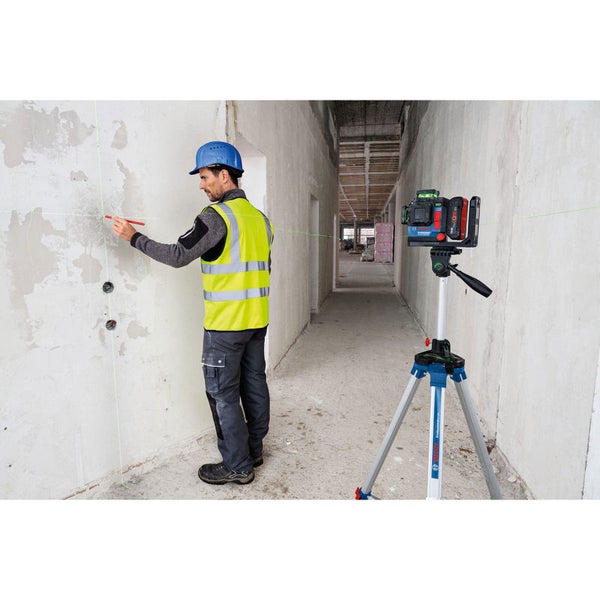 Ein Arbeiter markiert mit einem Stift eine Linie, die von einem Linienlaser an die Wand projiziert wird.