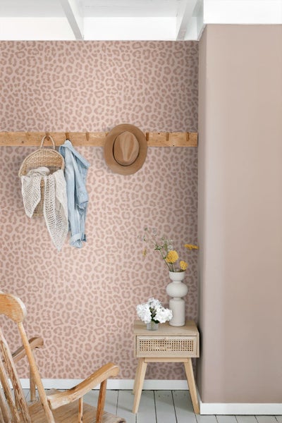 Vliestapete mit Leopardenmuster in einem Wohnraum mit Holzgarderobe, Beistelltisch und Holzstuhl.