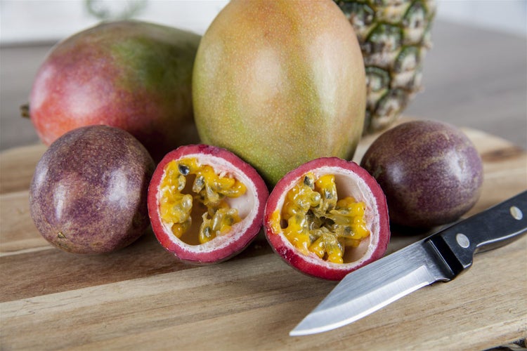 Exotische Früchte wie Mango, Maracuja und Ananas auf einem Schneidebrett