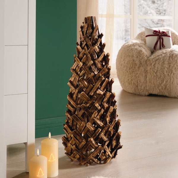 Dekorativer Weihnachtsbaum aus Holz in einem wohnlich dekorierten Raum neben zwei LED Kerzen mit Tannenbaummotiv.