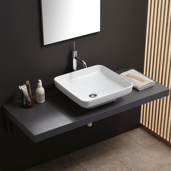 Quadratisches Aufsatzwaschbecken aus weißer Keramik auf einer dunkelgrauen Waschtischplatte mit verchromter Armatur in einem modernen Badezimmer.