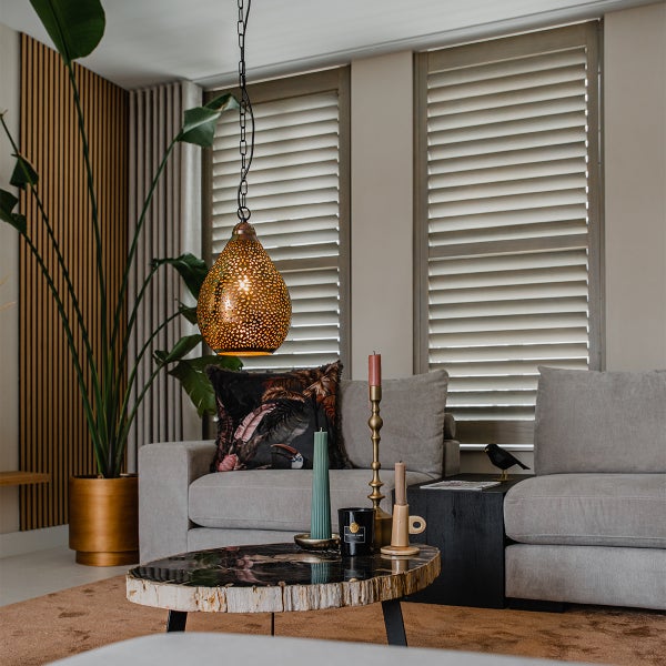 Wohnzimmer mit Pendelleuchte, Sofa, Couchtisch und Zimmerpflanze.