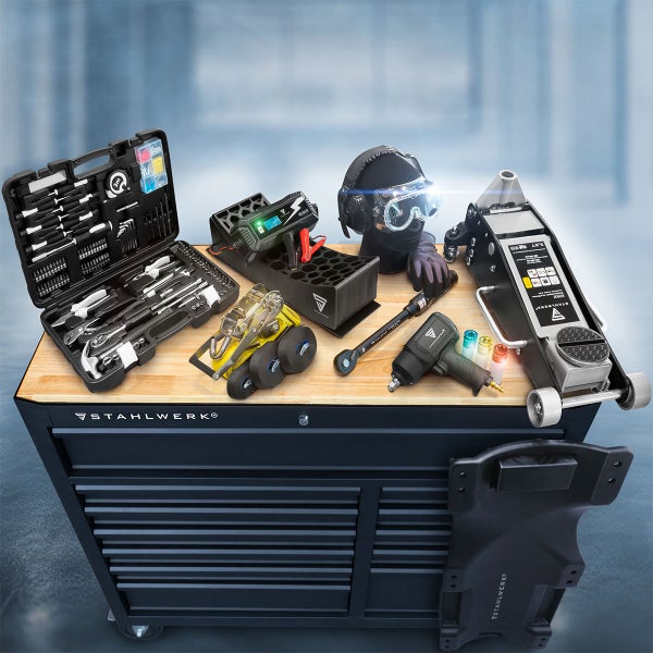 Werkstatteinrichtung mit Werkzeugkoffer, Batterieladegerät, Schweißhelm, Rollbrett, Rangierwagenheber, Drehmomentschlüssel und Schlagschrauber auf einem Werkzeugwagen