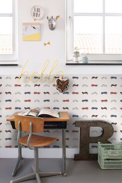 Gestreifte Kindertapete mit Oldtimer-Motiven hinter einem blauen Regal mit Spielzeug und Büchern in einem hellen Kinderzimmer.