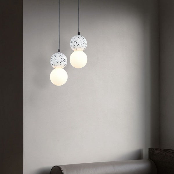 Zwei moderne Pendelleuchten mit Kugeldesign hängen im Raum.