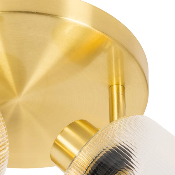 Detailaufnahme einer Deckenleuchte mit Messingelementen und geriffeltem Glasschirm.