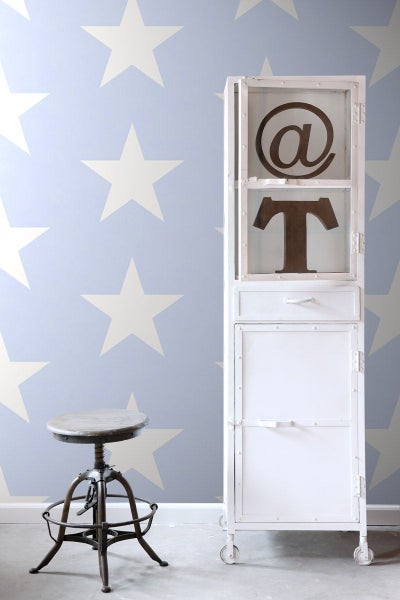 Szene mit einem Hocker, einem weißen Schrank mit Symbolen und einer Tapete mit Sternenmuster.