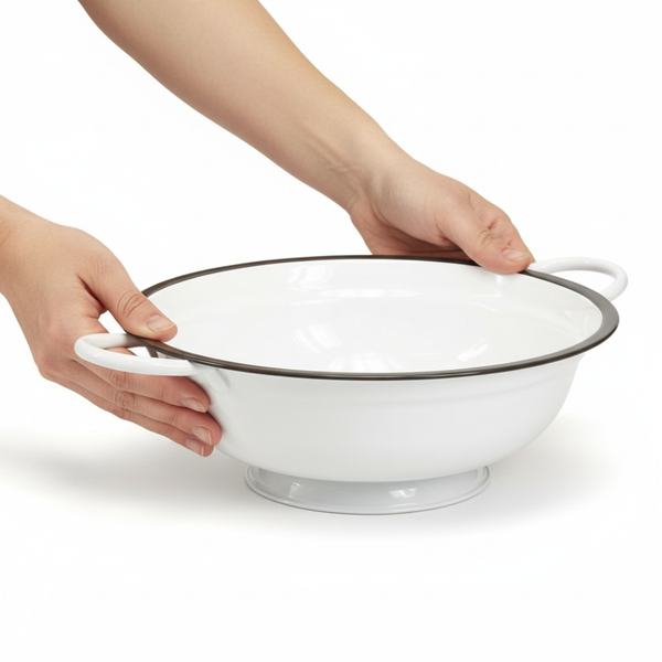 Weiße Emaille-Schüssel mit zwei Henkeln und dunklem Rand, gehalten von zwei Händen.