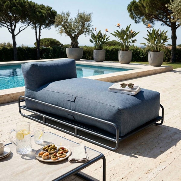 Moderne Gartenliege mit blauem Polster auf Metallgestell neben einem Pool mit Pflanzen und Beistelltisch.