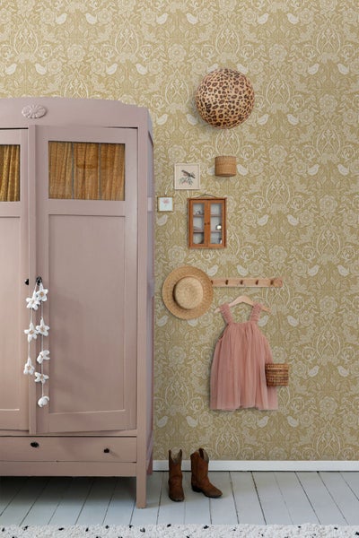 Vliestapete mit floralem Muster und Vögeln in einem Kinderzimmer mit rosa Schrank, Holzfußboden und Wanddekorationen im Vintage-Stil.