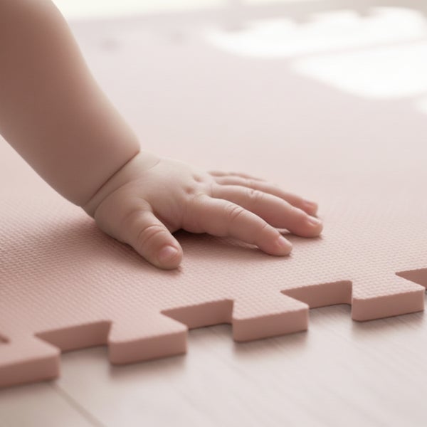 Nahaufnahme der Hand eines Babys auf einer strukturierten Schaumstoff-Puzzlematte.