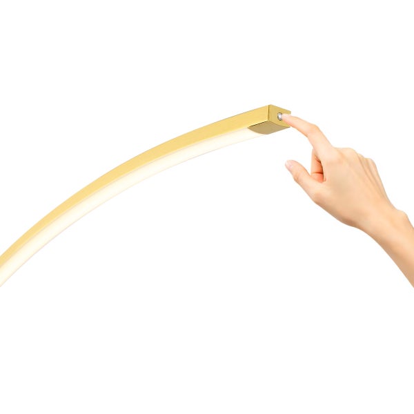 Eine Hand bedient den Tastschalter am Ende einer gebogenen goldfarbenen Lampe.