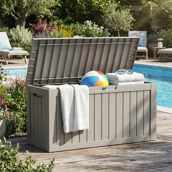 Offene Gartenbox aus Kunststoff in Holzoptik auf einer sonnigen Holzterrasse am Pool, gefüllt mit Handtüchern und einem Wasserball.