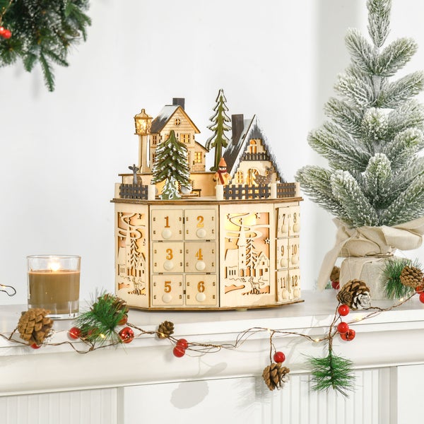 Adventskalender aus Holz mit 24 Schubladen und beleuchteter Winterszene, dekoriert mit Tanne, Kerze und Girlande mit Zapfen und roten Beeren.