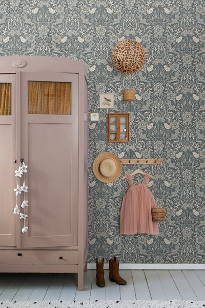 Vliestapete mit Vogel- und Blumenmuster in einem hellen Zimmer mit rosa Schrank, Wanddekoration und Kinderkleid.