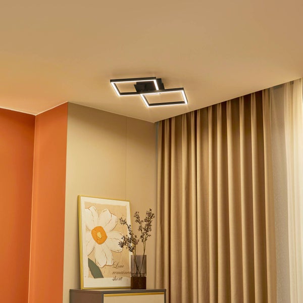 Moderne LED-Deckenleuchte mit zwei rechteckigen Rahmen in einem hellen Raum mit beigen Vorhängen und Wandbild.