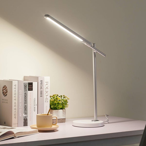 Moderne LED-Schreibtischleuchte mit verstellbarem Arm auf einem hellen, organisierten Schreibtisch neben Büchern und einer kleinen Pflanze.