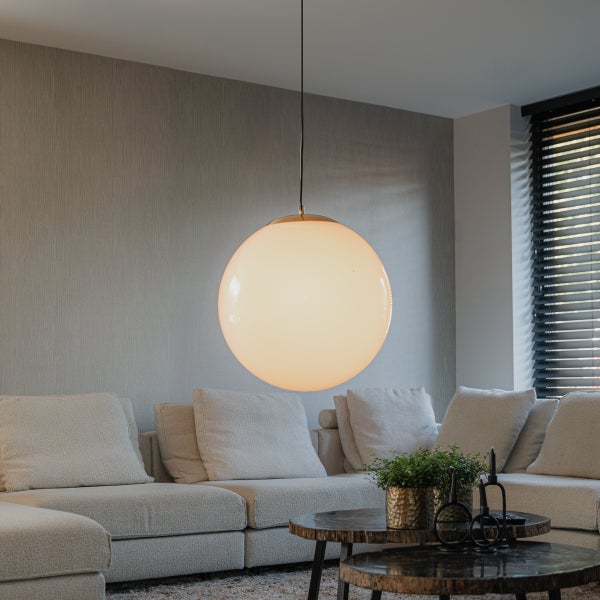 Innenaufnahme eines Wohnzimmers mit einer runden Hängelampe über einem Sofa und einem Couchtisch.