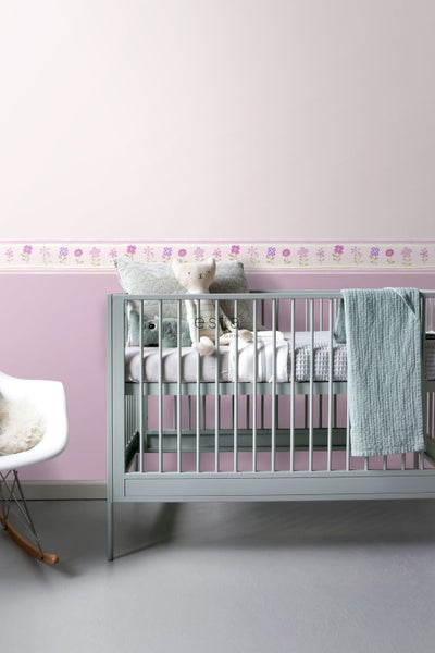 Kinderzimmer mit Babybett, floraler Bordüre und Schaukelstuhl
