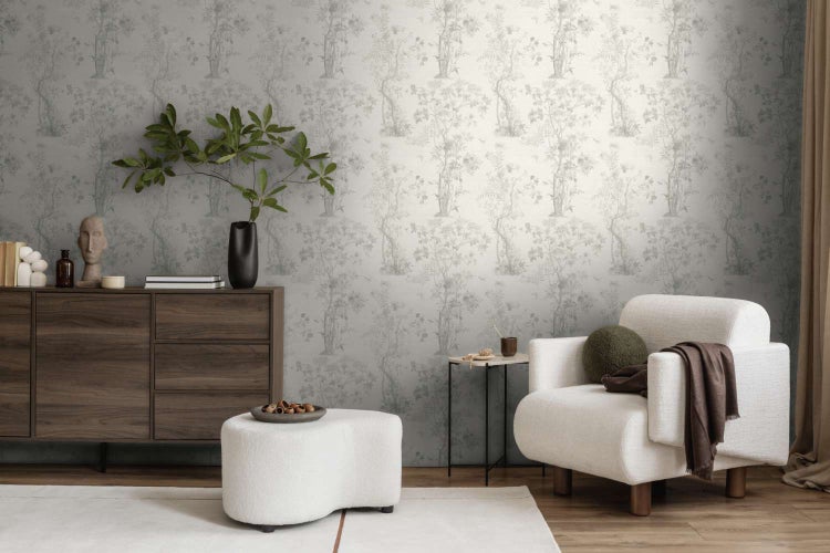 Wohnzimmer mit Vliestapete mit floralem Muster, dunkler Holzkommode, modernem Sessel und Hocker in einem hellen und stilvollen Einrichtungsstil.