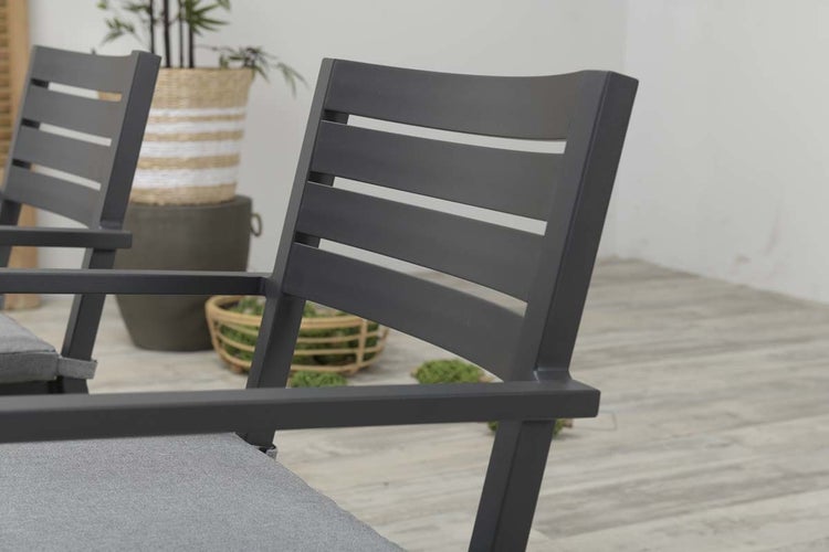 Detailansicht eines modernen Gartenstuhls aus Metall mit Armlehnen und horizontalen Lamellen in der Rückenlehne