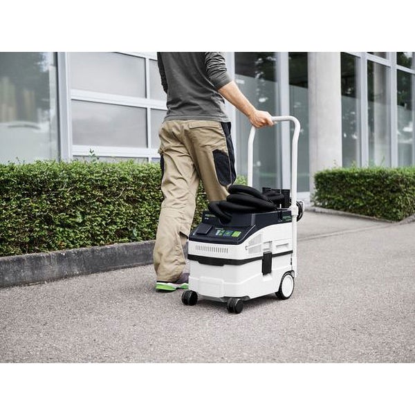 Handwerker zieht ein Festool Absaugmobil mit Schubbügel auf einem gepflasterten Weg.