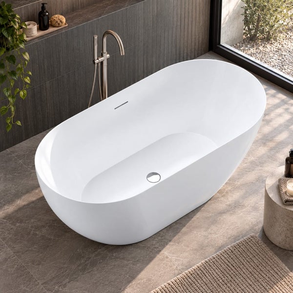 Freistehende ovale Badewanne in modernem Badezimmer mit Standarmatur vor einer Wand mit dunklen Fliesen.
