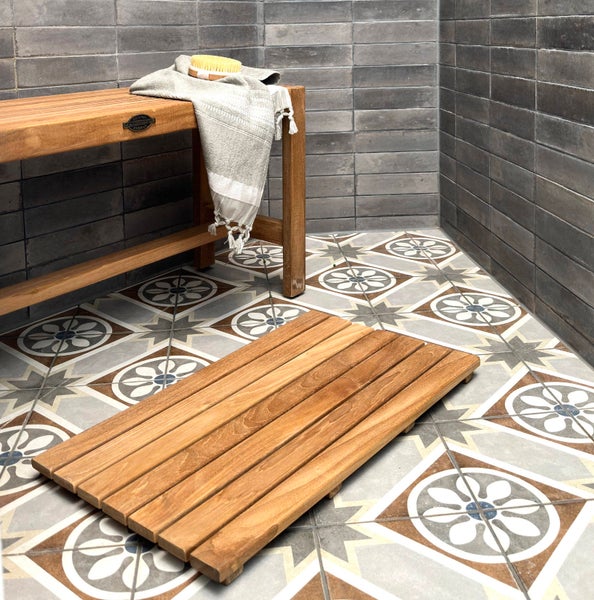 Badezimmer mit Holzbank, Handtuch, Badebürste, Duschmatte aus Holz und Fliesen mit Muster