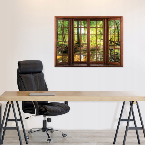 Wandbild mit Fensteroptik, das einen sonnigen Wald mit Bach zeigt, aufgehängt über einem Schreibtisch mit schwarzem Bürostuhl.
