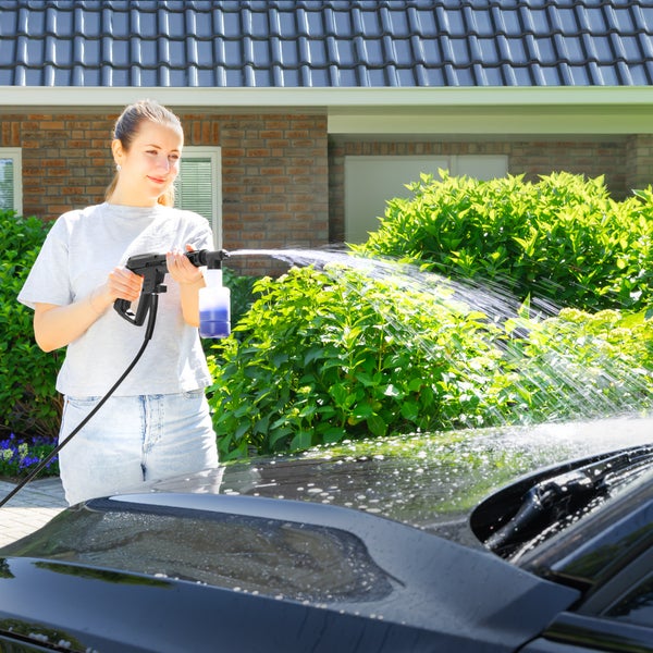 Hochdruckreiniger-Düse reinigt Pflastersteine mit einem starken Wasserstrahl im Garten vor Pflanzen.