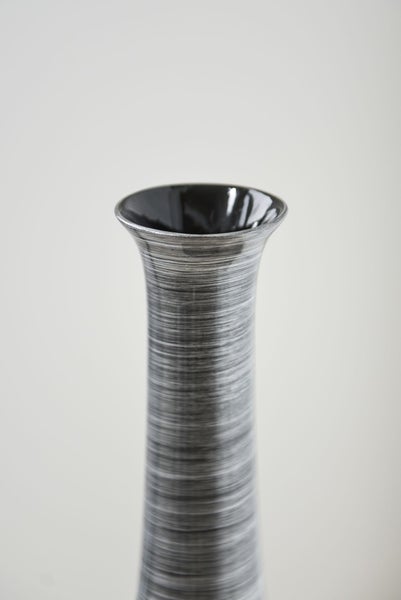 Schlanke hohe Vase mit horizontal strukturierter Oberfläche und ausgestelltem Rand.